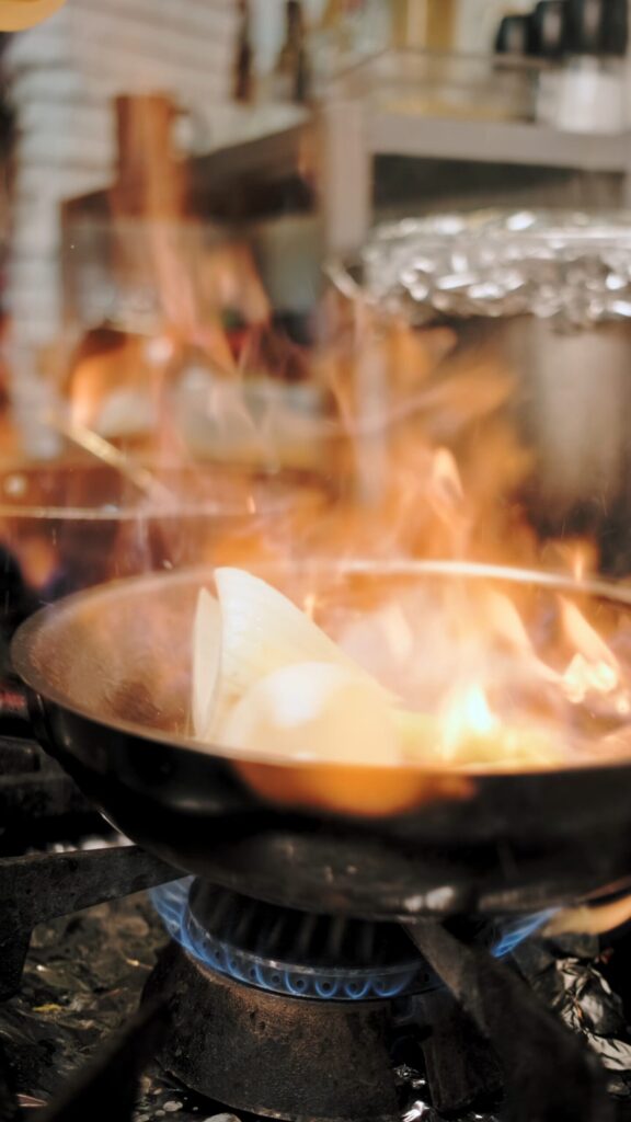 Patelnia z jedzeniem gotującym się na kuchence, wydobywające się aromatyczne zapachy.