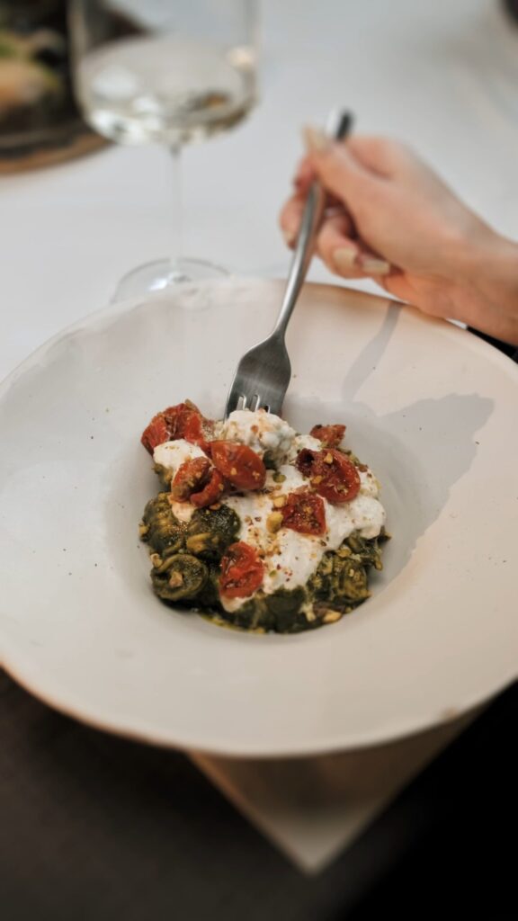 Osoba z widelcem w ręku, delektująca się posiłkiem na talerzu, w przyjemnej atmosferze.