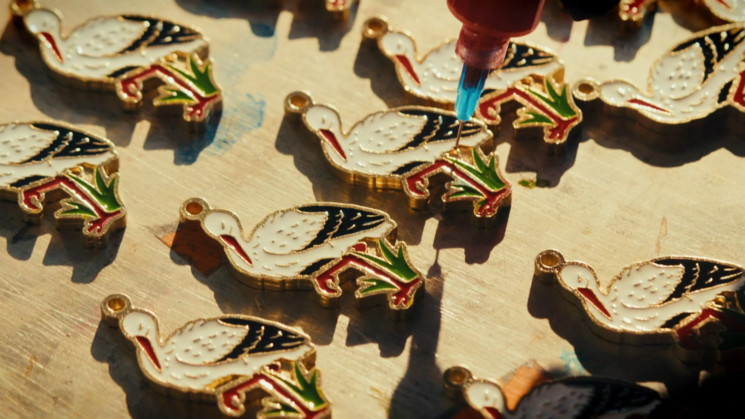 Proces malowania metalowej przypinki z bocianem firmy Pinswear.