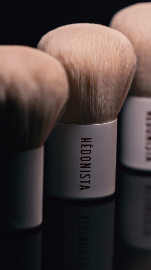 Cztery pędzle do makijażu marki Hedonista na czarnej powierzchni, ilustrujące ich unikalny design i jakość.