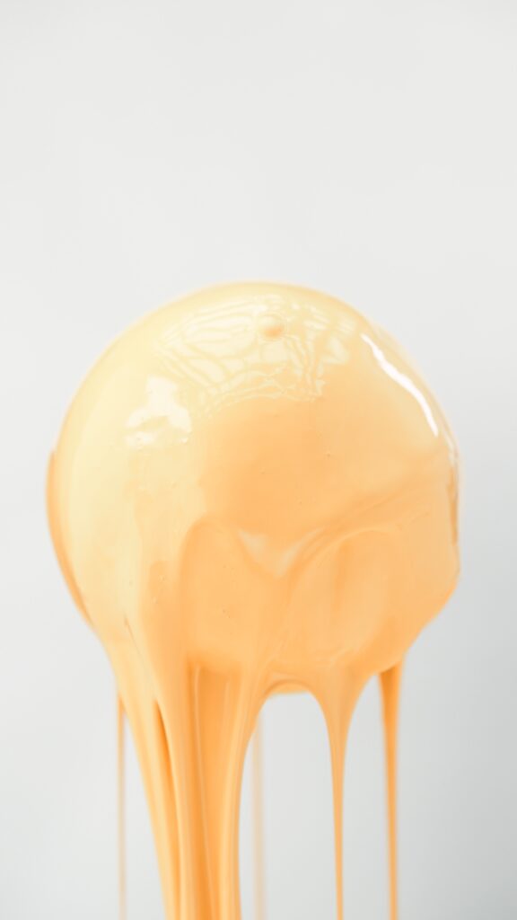 Zbliżenie na świeżą pomarańczę, oblana pomarańczową cieczą, która wygląda jak farba.