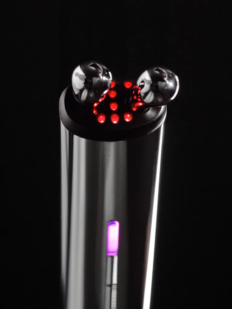 Zbliżenie na głowice AURA RF masażera liftingującego z czerwonym światłem LED.