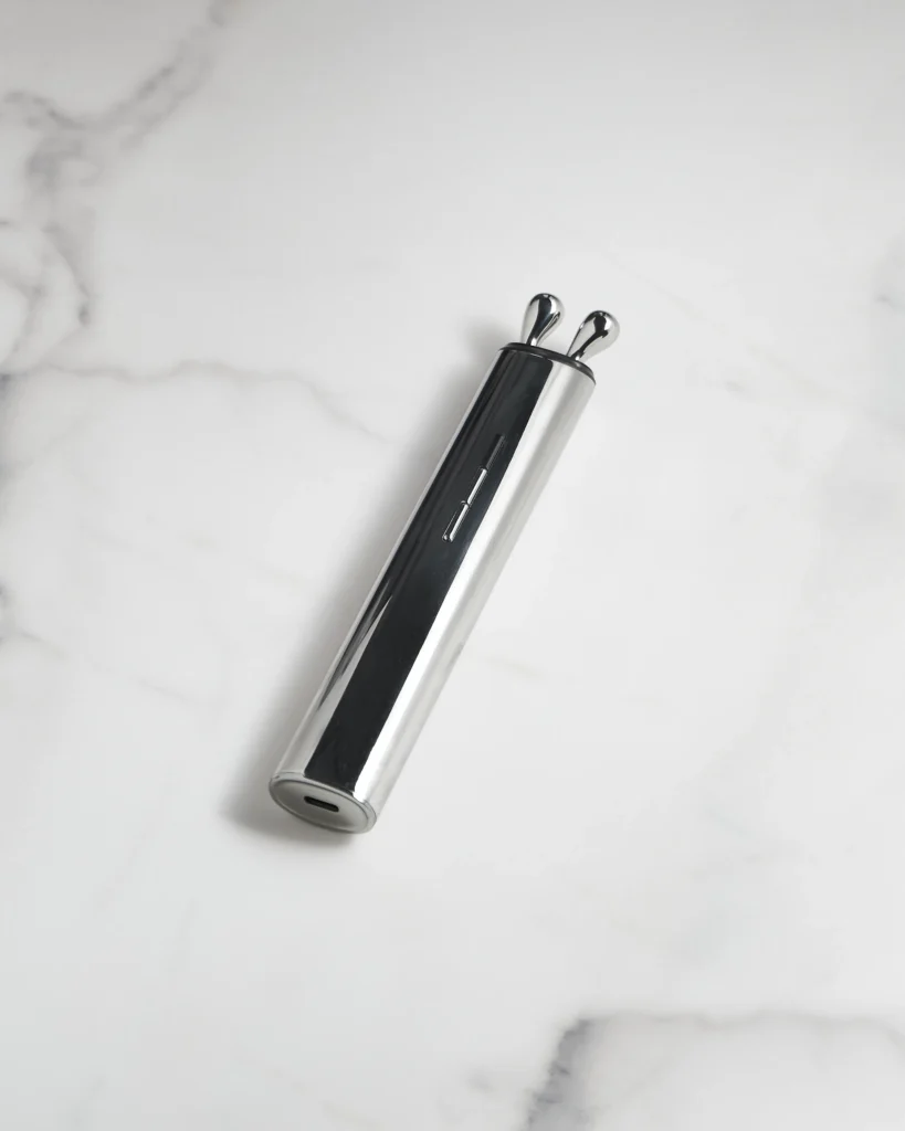 AURA RF masażer liftingujący leżący na białym marmurze, widok na port ładowania.